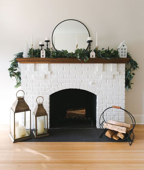 Holiday fireplace mantel, black and gold candle holders, white trees, and lanterns. Fireplace Lantern, Holiday Mantel Decor, Lanterns Fireplace, Scandinavian Holidays, Holiday Mantel, Holiday Table Decorations, Timeless Decor, Holiday Sparkle, Fireplace Mantel