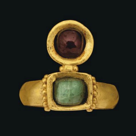 A ROMAN GOLD, EMERALD AND GARNET RING   CIRCA 4TH CENTURY A.D.   With solid gold plain hoop, slightly raised rectangular box-set bezel with row of granulation either side, set with a cabochon emerald, the circular box-set bezel projection set with garnet bead  Bezel ¾ in. (2 cm.) wide Heirloom Garnet Jewelry With Bezel Setting, Antique Ruby Cabochon Ring Gift, Medieval Metal Jewelry With Antique Finish, Antique Ruby Cabochon Ring, Medieval Brass Jewelry With Antique Finish, Imperiul Roman, Ancient Roman Jewelry, Byzantine Jewelry, Ancient Jewels