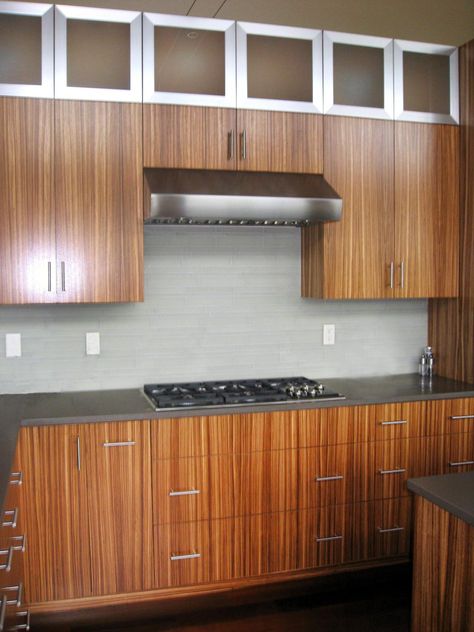 The clients didn't want the typical kitchen in their new home, so Caswell uses zebra wood and stainless-steel upper cabinets to make the kitchen feel unique custom and modern. Zebrawood Cabinets, Wood Cabinets Kitchen, Interior Millwork, House Beautiful Kitchens, Hgtv Design, Best Flooring For Kitchen, Spanish Style Kitchen, Timber Kitchen, Upper Kitchen Cabinets