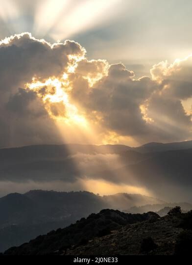 Bright sun rays light shining through dark clouds over mountain at sunset. Dramatic sky in winter Stock Photo Sun Breaking Through Storm Clouds, God Rays Sunlight, Cloudy Sky Photography, Abstract Light Photography, Dramatic Clouds Photography, Sunset Clouds Photography, Cloud Reference Photo, Sun Peaking Through Clouds, Sunset Lighting Reference