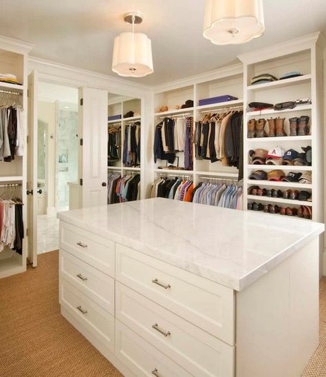 Stunning walk-in closet with floor to ceiling shelving and clothes rails and a center closet island. The ceiling height cabinetry is finished with crown molding. The central closet island with drawers features brushed nickel hardware and marble countertops. A pair of Barbara Barry Simple Scallop Pendants hang over the island. The floors are carpets in a wall to wall sisal carpeting. Walking Closet Ideas, Master Closet Design, Closet Island, Walking Closet, Dream Closet Design, Walk In Closet Design, Closet Layout, Closet Remodel, Closet Room