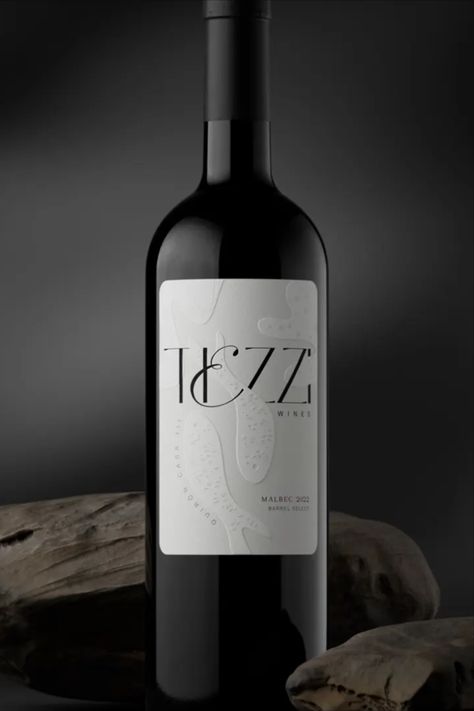 Every good art exhibition needs wine, so why not pick a bottle that looks like art itself? Argentina's Mamba Estudio makes a real contender with their gorgeous work for Tiezzi Wines. While the palette is a simple, no-nonsense black and white, next-level embossing and typography make the label stand out. Abstract fish swim through the swirly logomark, and they even have tiny little scales that look like a pleasure to touch— a wine for the real sensualists, so to speak. Wine Label Typography, Wine Etiquette Design, Wine Typography, Wine Bottle Logo, Champagne Packaging, White Wine Labels, Wine Etiquette, Bottle Logo, Need Wine