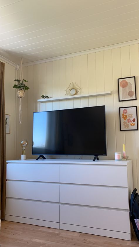 Tv area with a mirror, plants, light and pictures in gold, pink and white tones. Tv Mounted On Wall In Bedroom, Small Bedroom Tv Stand Ideas, Tv On Top Of Dresser Bedrooms, White Dresser With Tv On Top, Tv On Bedroom Wall, Bedroom Inspo With Tv, Room Tv Ideas Bedrooms, Tv Ideas For Bedroom, Tv Small Bedroom