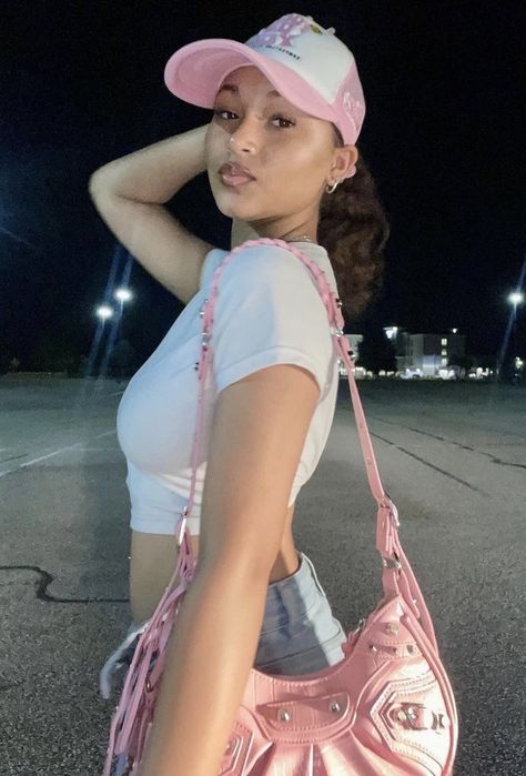 Girl with a curly ponytail is wearing a white crop top and trucker hat and a pink balenciaga le Cagole purse Pink Trucker Hat Aesthetic, Pink Hat Outfit Baseball Caps, Balenciaga Purse Outfit, Pink Trucker Hat Outfit, Pink Baseball Cap Outfit, Y2k Outfits White, Aesthetic Belly Button Piercing, Pink Cap Outfit, Pink Y2k Fashion