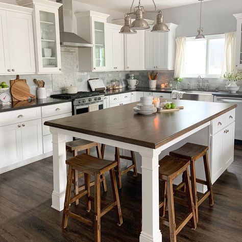 A nickel multi-head pendant light hangs above wooden bar stools arranged under one end of a kitchen island with legs. The white island features a dark stained wood countertop and cabinets with nickel knobs on the other end. Open Kitchen With Breakfast Counter, Kitchen Island With Chairs, Island With Chairs, White Kitchen Island Ideas, Kitchen With Bar Counter, Kitchen Island End Panels, Kitchen Island With Legs, Beadboard Kitchen, Chairs For Kitchen Island