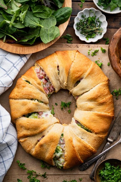 Ham and cheese crescent rolls bake in a ring for an easy-to-serve, easy-to-slice weeknight dinner or crowd-pleasing appetizer. The ham, cheddar, and broccoli crescent ring is flaky, golden brown, and stuffed with a creamy, cheesy, and flavorful filling. It's delicious alongside a simple salad, potato chips, or fresh fruit. Ham And Cheese Wreath Crescent Ring, Ham And Cheese Crescent Ring, Ham And Cheese Crescent Roll Bake, Broccoli Ham Ring, Recipes With Crescent Rolls, Ham And Cheese Crescent Rolls, Ham And Cheese Crescent, Cheese Crescent Roll Recipes, Crescent Roll Bake