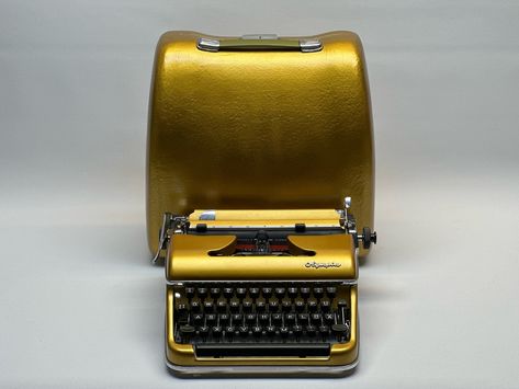 Vintage Olympia SM3 Gold Typewriter with Gold Bag - Classic Manual Typewriter, Fully Functional and Serviced, Retro Office Decor, Collectible Writing Machine Description: Experience the elegance of the Olympia SM3 Gold Typewriter, now in a luxurious gold finish. This classic manual typewriter is not only a beautiful collector’s item but also fully functional and ideal for writers, collectors, and vintage enthusiasts. • Luxurious Gold Finish: Stunning gold finish that makes it a statement ... Olympia Typewriter, Retro Office Decor, Typewriter Vintage, Manual Typewriter, Folgers Coffee, Writing Machine, Retro Office, Gold Bag, Vintage Typewriters