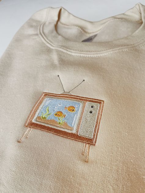 "Embroidered Aquarium Television Sweatshirt -Embroidered on a cotton/polyester blend crewneck sweatshirt, this design is simple and minimalistic, perfect for every outfit! -Embroidery design measures 4.5\" x 3\". -See product pictures for shirt sizing chart. **SWEATSHIRTS ARE IN UNISEX SIZING AND RUN TRUE TO SIZE. -All sweatshirts are handmade on an embroidery machine so there may be slight differences, but we only sell the sweatshirts that meet our high-quality standards. -To maintain the quali Embroidery Clothes Sweatshirts & Hoodies, Cotton Crew Neck Sweatshirt With Embroidered Patch, Embroidery Inspiration Clothing Sweatshirts & Hoodies, Hoodie Embroidery Ideas, Cute Embroidered Hoodie For Streetwear, Embroidered Crew Neck T-shirt For Streetwear, Sweatshirt Embroidery Ideas, Embroidered Crew Neck Sweatshirt For Streetwear, Crewneck Embroidery