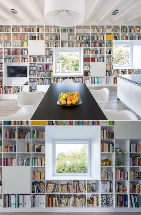 An entire wall is filled with bookshelves and includes window seats. Wall Bookshelves Under Window, Window Wall Bookshelves, Bookcases Under Windows, Long Wall Book Shelf, Bookshelves Around Window, Bookshelf Around Window, Full Wall Bookshelf With Window, Ikea Long Wall Shelves Books, Windowseat Bookcase