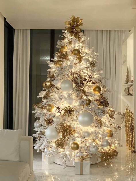 A beautifully decorated Christmas tree with a luxurious and elegant theme. The tree is adorned primarily in shades of white and gold, creating a sophisticated and cohesive look. White Christmas Tree With Gold Ornaments, White Christmas Tree Gold Decorations, White Christmas Tree Topper Ideas, White Tree Decorating Ideas, White And Gold Christmas Decor Ideas, White And Gold Christmas Tree Ideas, White Christmas Trees Decorated, Christmas Tree Gold And White, White Christmas Tree Ideas Color Schemes