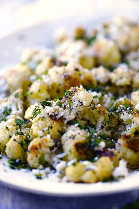 This Greek Roasted Cauliflower is seasoned with garlic, oregano, and lemon zest, then topped with crumbled feta, fresh herbs, lemon juice, and olive oil. Alternatively you can make a yogurt sauce to go on top. This will be your new favorite low carb Greek side dish! Feta Cauliflower Bake, Best Greek Side Dishes, Keto Greek Recipes, Greek Dishes Recipes, Greek Side Dishes Vegetables, Greek Vegetables Side, Meditrainian Diet, Sides With Fish, Low Carb Mediterranean Recipes