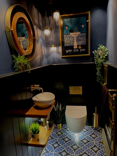 Downstairs cloakroom with wall hung toilet and sink. Victorian style floor sets off the lower tongue and groove boarding painted in F&B Railings and the upper wall and ceiling painted in F&B Stiffkey Blue. Brushed gold flush plate, taps and accessories add to the glamorous feel. Warm oak floating shelves, plants,  and a vintage style poster in a gold frame soften the look. A cascading chandelier, low power spot lights and lighting under the loo and sink shelves provide plenty of warm light Industrial Bathroom Ideas, Small Downstairs Toilet, Bathroom Ideas On A Budget, Downstairs Toilet, Industrial Bathroom, Small Bathroom Ideas On A Budget, Small Bathroom Ideas Modern, Bathroom Design Inspiration, Tiny Bathrooms