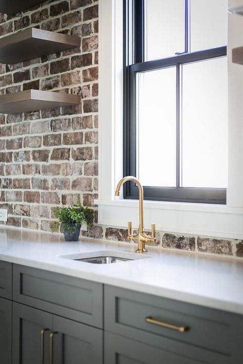 Gray shaker pantry cabinets with brass pulls topped with white quartz countertops in a kitchen showcasing exposed red brick walls and brown wood floating shelves. Kitchen With Brick, Exposed Brick Kitchen, Brick Wall Kitchen, Brick Backsplash Kitchen, Kitchen Finishes, Brick Kitchen, Brick Backsplash, Kitchen White, Gorgeous Kitchens