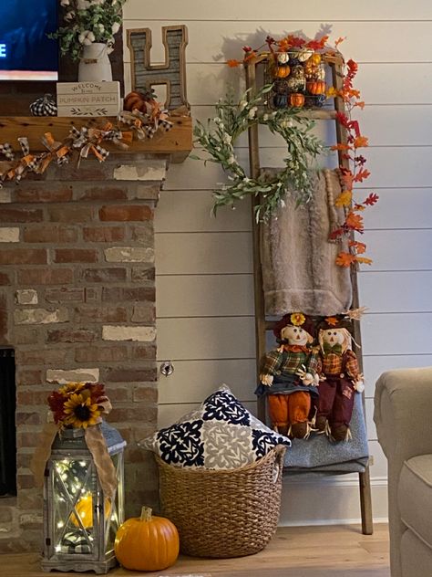 The blanket ladder has fall additions of scarecrows sitting on the ladder as well as a Garland of leaves hanging from the top. I added a couple of pumpkins to this side of the mantle as well as hanging my DIY fabric strip Garland. Decorating A Ladder For Fall, Autumn Ladder Decor, Fall Decor With Ladders, How To Decorate Blanket Ladder, Fall Decor Ladder, Ladder Fall Decor, Halloween Blanket Ladder, Fall Blanket Ladder Decor, Fall Blanket Ladder