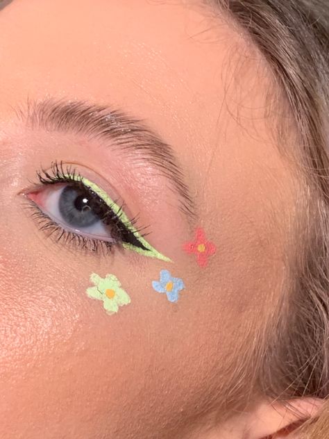 black winged eyeliner w pastel green outline, and 3 pink blue and green flowers going from cheek bone to brow Flower Art Makeup, Cute Flower Makeup, Flowers Eye Makeup, Flower Halloween Makeup, Cute Face Painting Aesthetic, Flower Make Up, Flower Makeup Aesthetic, Floral Eyeliner, Face Art Makeup Paint Ideas