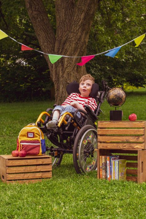 A five year old boy in a white with red t-shirt in a yellow wheelchair sits under the tree surrounded by books in sodden crate, globus, backpack and apples. Above his head a colorful flags Back To School Poses, School Poses, Wheelchair Photography, Back To School Photoshoot, School Photoshoot, Photographs Of People, Special Needs Kids, Autumn Photography, Photo Reference