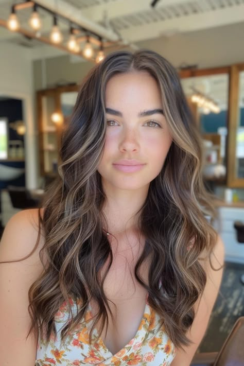 Woman with long, wavy hair and a floral dress standing indoors. Hazel Highlights, Natural Highlights For Brown Hair, Dark Brown With Caramel Highlights, Dark Brown With Caramel, Caramel Highlights On Dark Hair, Dark Caramel Highlights, Highlights On Dark Brown Hair, Dark Brown Hair Rich, Subtle Brown Highlights