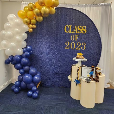 Throw an exciting Graduation party and create a splendid backdrop decor. Hang white curtains and set a round metal backdrop stand covered in a navy-blue shimmer spandex cover in front. Arrange a chic gold, white, & navy-blue balloon garland and stick gold glitter stickers spelling CLASS OF 2023 to add instant visual elegance. Arrange beige spandex covered cylinder pedestal stands exhibiting the party cake and other party related decorative accents and make your backdrop stand out. Elegant Graduation Party Decorations, Blue Graduation Decorations, Metal Backdrop Stand, Elegant Graduation Party, Metal Backdrop, Cylinder Pedestal, High School Graduation Party Decorations, Boy Graduation, Gold Graduation Party