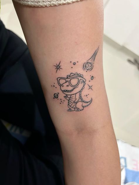 Funny Space Tattoo, Mother Son Dinosaur Tattoo, Cute Dinosaur Tattoo Ideas, Cute Dino Tattoo Ideas, Funny Dinosaur Tattoo, Space Dragon Tattoo, Tiny T-rex Tattoo, Little Dinosaur Tattoo, Dino Tattoo Cute