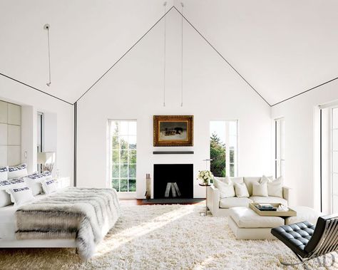 In the master bedroom, a J. H. Dolph painting hangs above a fireplace with Creel and Gow selenite logs; the bedding by Nancy Stanley Waud Fine Linens is topped with a Dennis Basso fur coverlet, the sofa is by Flexform, and the Mies van der Rohe chair is by Knoll Nantucket Cottage, All White Bedroom, White Fireplace, Bedroom Fireplace, Bedroom Decor Cozy, Design Seeds, In The Corner, Vaulted Ceiling, White Bedroom