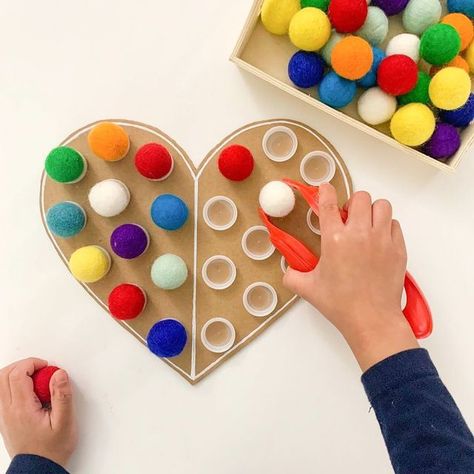 Two to Love - DIY Learning | Sensory | Crafts for Kids on Instagram: "❤️ Heart Symmetry 🌈 Here’s a fun and colorful way we practiced symmetry and fine motor skills last year! I simply cut out heart shape from cardboard and hot glued bottle caps on it to make this simple DIY. Took it out today for the twins to play with this afternoon. They are really into these colorful felt balls so we’ll see how it goes when they get home from school.😊 🙋🏻‍♀️Have you incorporated the concept of Symmetry in Sensory Crafts For Kids, Preschool Valentines Activities, Hearts Paper Crafts, Montessori Diy, Sensory Crafts, Montessori Toddler Activities, Preschool Fine Motor, Valentine Activities, Fine Motor Skills Activities