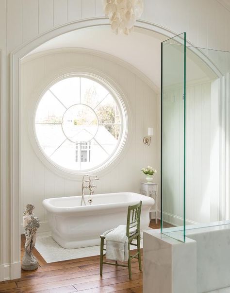 An arched bathtub alcove is clad in vertical shiplap trim fitted with a large round mirror flanked by sconces illuminating a Waterworks Empire Freestanding Bathtub paired with a vintage style hand-held tub filler. Ivory Bathroom, Bathtub Alcove, Round Windows, Standing Bathtub, Refinish Bathtub, Porthole Window, Rose Window, Round Window, Cottage Bathroom