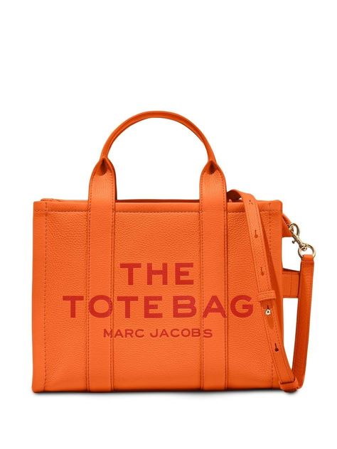 The Leather small tote bag from Marc Jacobs featuring orange, leather, slogan print to the front, logo patch to the rear, top zip fastening, two rounded top handles, adjustable detachable shoulder strap and single flat side handle. Marc Jacobs Tote, Small Tote Bag, Mini Tote Bag, The Tote Bag, Marc Jacobs Bag, Orange Bag, Leather Cap, Medium Tote, Orange Leather