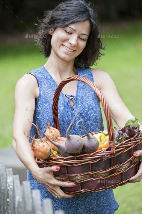 Woman standing in a garden holding a basket of vegetables. by Mint_Images. Woman standing in a garden holding a basket of vegetables. #Sponsored #garden, #standing, #Woman, #holding Holding Basket Pose, Woman Looking Down, Standing Woman, Body Reference, Woman Standing, Art Tips, Woman Face, A Garden, Anatomy