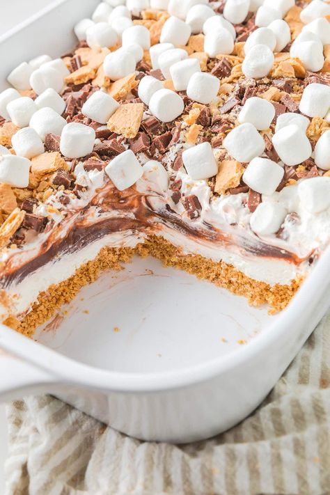 S'mores Lush Cake in a baking dish Smores Pudding Pie, Smores Dirt Cake, No Bake Smores Dessert, S’mores Casserole Recipe, Smores Pudding Dessert, Smores Fluff, S’mores Themed Desserts, S’mores Dessert, Smores Cakes