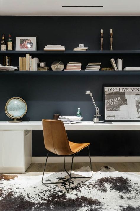 a contemporary home office with a black wall and open shelves, a white desk, an amber leather chair and an animal skin rug Masculine Home Offices, Black Office Furniture, Home Office Dark, White Desk Office, Black Wall Decor, Contemporary Home Office, White Desk, Built In Furniture, White Desks