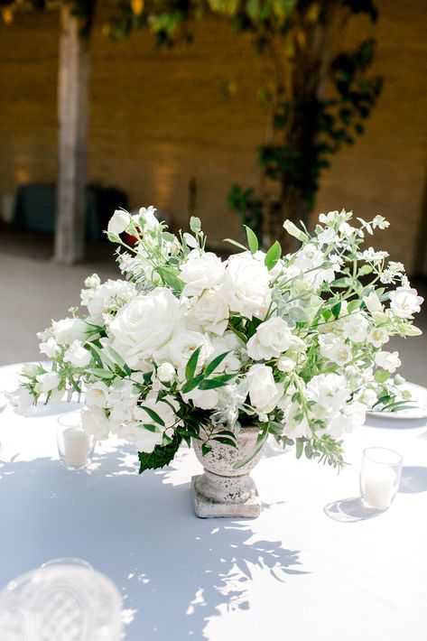 Round Table centerpiece, Stone compote with white flowers and eucalyptus greenery. Santa Barbara Historical Museum Wedding with Tricia Dahlgren Events, Haute Blossoms Floral & Brooke Borough Photography. White Compote Arrangement, White Rose Floral Arrangements, Compote Centerpiece Wedding, White Table Centerpieces, Round Table Arrangements, Round Table Wedding Centerpieces, White Centerpiece Wedding, White And Green Centerpieces, All White Wedding Flowers