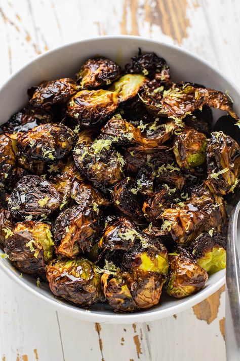 These crispy roasted restaurant-style brussels sprouts have quickly become our favorite way to prepare brussels sprouts. These brussels are halved and roasted cut side down on a hot baking sheet until they're golden brown and ultra tender. While you can certainly eat them as is, they're finished with a drizzle of balsamic glaze, honey, and freshly zested lemon. #brusselsprouts #roastedveggies Blackened Brussel Sprouts Recipe, Sticky Brussel Sprouts, Crispy Asian Brussel Sprouts, Tender Brussel Sprout Recipes, Roasted Brussel Sprouts Oven Crispy, Restaurant Style Crispy Brussel Sprouts, Brussel Sprout Recipes Lemon, Clean Eating Brussel Sprout Recipes, Best Roasted Brussels Sprouts