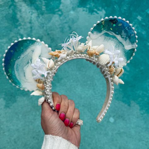 For all my mermaid girlies! These resin ocean wave mouse ears are absolutely stunning. The mouse ears headband is accented with pearls and sea shells, and the waves sparkle with bits of blue. A perfect complement to any mermaid outfit or Ariel inspired look for the parks, these ears are mer-made for you :). Due to the handmade nature of my ears and the artistic quality of resin, each pair will vary slightly, making yours unique and just for you. Just like real ocean waves, no two will be exactly Moana Gifts, Mini Mouse Ears, Diy Disney Ears, Disney Ears Headband, Mermaid Stuff, Disney Themed Outfits, Hello Holiday, Mermaid Core, Ocean Resin