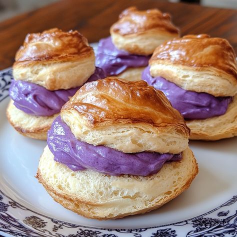 💜✨ Ube Cream Puffs: Delight in the creamy, purple magic of ube-filled pastries! 💜 #DessertHeaven #UbeLovers Ube Cream Puffs Ingredients: Butter (1/2 cup) Water (1 cup) Flour (1 cup) Eggs (4) Ube jam (1 cup) Heavy cream (1 cup) Sugar (1/4 cup) Vanilla extract (1 tsp) Instructions: Boil butter and water, stir in flour until a ball forms. Cool slightly, beat in eggs one at a time. Pipe onto baking sheet, bake at 400°F for 25 minutes. Whip ube jam, heavy cream, sugar, and vanilla. Fill puffs.... Ube Puff Pastry, Ube Cream Puffs, Ube Pastry, Anpan Recipe, Filled Pastries, Ube Jam, Purple Magic, Instagram Recipes, Dessert Tea