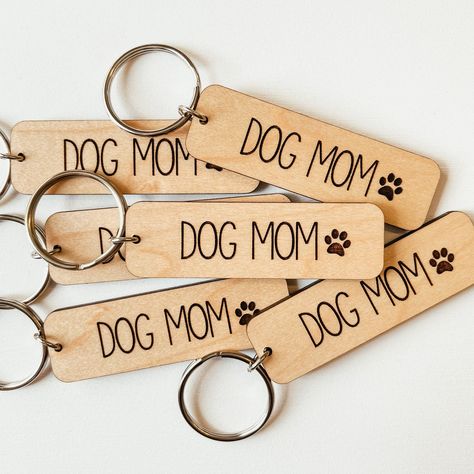 "Interested in a bulk order? Send us a message to see if your order qualifies for bulk order pricing! Our wooden keychains are cut from premium-grade, laminated maple and engraved with our studio laser. Each keychain measures 2.5 inches wide x 0.75 inches tall x 1/8\" thick. Because these are cut from real wood, there will be slight variations in colour and wood grain than what is shown in the photos. PROCESSING TIME Our shop processing time varies by item, but can be found on each product listi Dog Mom Keychain, Paw Print Keychain, Dog Quote, Laser Cut Wood Crafts, Black Barn, Mom Keychain, Wood Keychain, Wooden Keychain, Dog Keychain