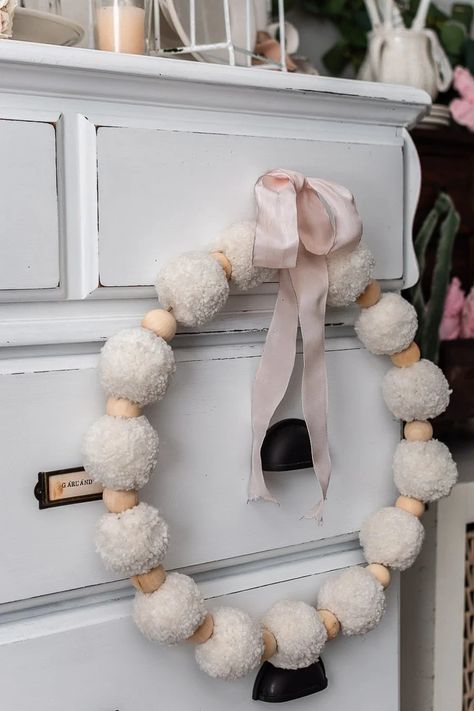 wood bead and pom pom wreath, pink ribbon, vintage white dresser White Pom Pom Wreath, Pom Pom Wreath Diy, Vintage White Dresser, Spindle Candlesticks, Heart Wreath Form, Pearl Garland, Thrifty Diy, Pom Pom Wreath, Heart Shaped Wreaths