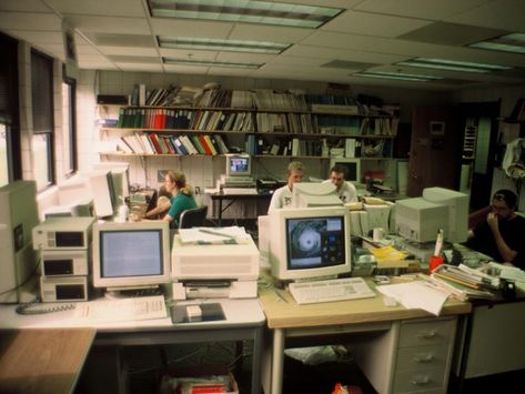 Office with computers and bookshelves, people sitting at desks, circa early 1990s. Computer Lab Aesthetic, 90s Office, Sitting At Desk, Old Office, Office Aesthetic, Computer Desks, Retro Office, Desk Inspo, Retro Room