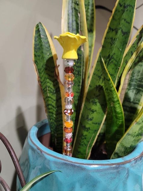 How to Make Beaded Garden Stakes: Bling For Your Plants Diy Plant Stakes Flower Pots, Bead Garden Stakes, Beaded Plant Stakes, Garden Fairy Wands, Jean Basket, Spilled Flower Pot Ideas, Beaded Garden Stakes, Spilled Flower Pot, Plant Sticks