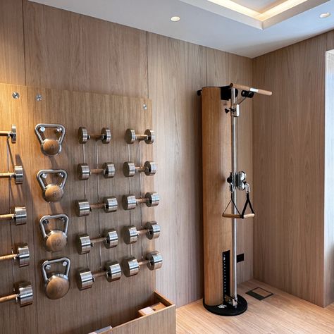 A luxury home gym in London featuring a triple storage wall in oak and steel. The wall contains Paragon Studio diabolo dumbbells, kettlebells and other accessories. The Nohrd Slim Beam cable machine in oak has been specified by the client to add an extra weight training option. #gym #homegym #gymstorage #luxurygym #gymdesign Kettlebell Gym Design, Coastal Home Gym, Ikea Home Gym, Home Weight Room, Small Storage Room Ideas, Gym Home Design, At Home Gym Ideas, Gym Storage Ideas, Kettlebell Storage