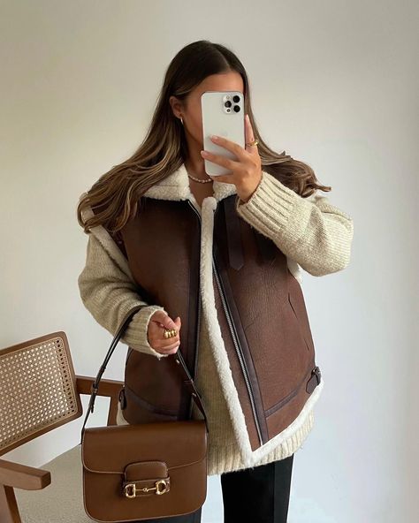 This ensemble features a cream knit sweater providing a cozy foundation, expertly layered with a sumptuous leather vest lined with soft shearling perfect juxtaposition of textures. Complementing the upper garments, a caramel-colored crossbody bag adds functional sophistication, making it an essential companion for the discerning style maven on the go. #SpringFashion #LeatherLayers #Knitwear #OutfitInspo Winter Warm Outfits, Trendy Cardigans, Oversized Wool Coat, Faux Suede Vest, Faux Leather Vest, Vest Outfit, Cream Knit Sweater, Shearling Vest, Suede Vest