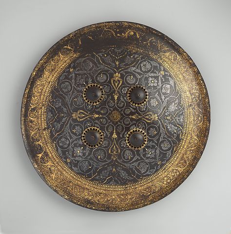 Of sturdy construction, and suitable for battle, this is a rare example of a distinctive type of seventeenth-century shield made in Muslim India, possibly the Deccan. In both conception and execution its chiseled and damascened ornamentation compares closely to that of only two other known shields: one in the collection of the Furusiyya Art Foundation (inv Persian Shield, History Jewelry, Art Foundation, Female Armor, Arm Armor, Fantasy Armor, Historical Art, Ancient Civilizations, Metropolitan Museum Of Art