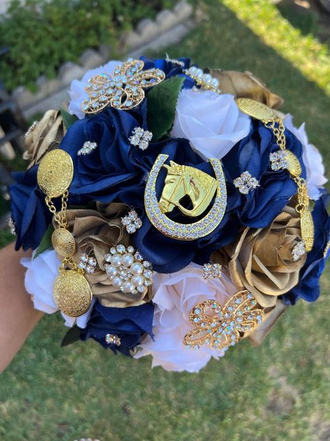 Handmade Quinceañera Bouquet/ Wedding.  With Ivory, Gold and Navy Blue Roses. Finished off with Gold brooches with Aztec and Horseshoe style Brooches.  *Please note brooches can change in style due to availability.* Decor / color combinations can be changed upon request. {This is a made to order Bouquet} Charro Quinceanera Bouquet, Quinceanera Dresses Navy Blue And Gold, Navy Blue And Gold Quinceanera Theme, Blue Charro Quinceanera Theme, Navy Blue And Gold Quinceanera Dresses, Navy Blue And Gold Quince, Charo Quinceanera Dresses, Blue Charro Quinceanera Dresses, Royal Blue Quinceanera Ideas