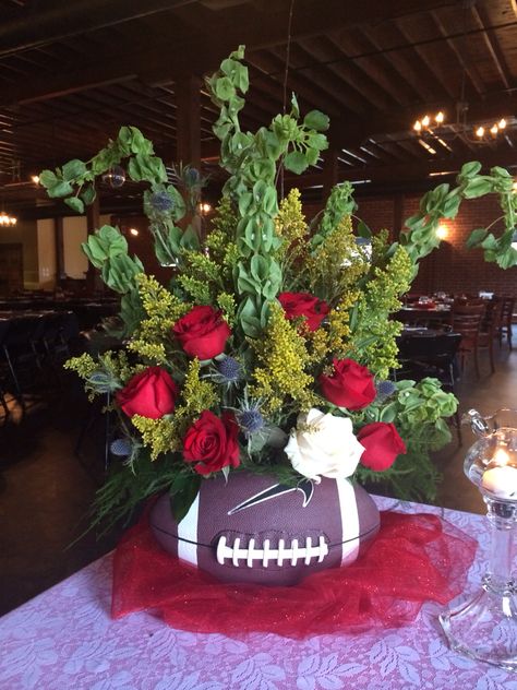 Football vase filled with flowers! Take a football and cut an oval out of the top and stuff with styrofoam greenery, then create a beautiful arrangement! Football Floral Arrangement, Football Arrangements, Football Vase, Sports Banquet Decorations, Bengal Football, 49ers Birthday Party, Football Centerpiece, Razorback Wreath, Uga Graduation