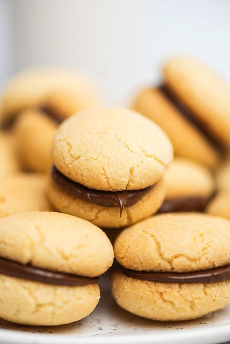 Have you ever tasted baci de dama? These mini Italian chocolate filled sandwich cookies are made with chocolate and vanilla. One or two of these Italian cookies with chocolate in the middle will definitely put a smile on your face. The buttery vanilla cookies are sandwiched together with chocolate so you can enjoy both flavors in every bite. This version of these chocolate filled cookies is made without hazelnuts. Baci di dama are mini Italian chocolate sandwich cookies. #cookies #italian Tea Party Food Ideas, C Is For Cookie, Tea Party Menu, Red Wine Sangria, Cookie Sandwich Recipes, Amaretti Cookies, Wine Sangria, Italian Chocolate, Peanut Butter Cupcakes