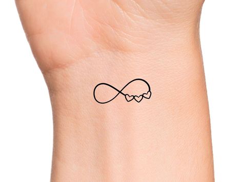 Infinity 3 Hearts Temporary Tattoo Size: The size of this Temporary Tattoo is approximately 1 inch in length. If you would like this design in a smaller or larger size that isn't already listed, please message us directly on Etsy BEFORE placing your order so we can provide you with accurate pricing. Directions: 1. Cut excess paper around tattoo with scissors to eliminate any unnecessary adhesive on your skin after applying. 2. Peel away and discard the clear plastic layer. 3. Apply the tattoo im Fine Line Wedding Band Tattoo, 3 Heart Tattoos For Women, 3 Intertwined Hearts Tattoo, Tattoo Three Hearts, 3 Interlocking Hearts Tattoo, 3 Hearts Tattoo On Wrist, Cute Family Tattoos, Family Related Tattoos, Small Mom Tattoos