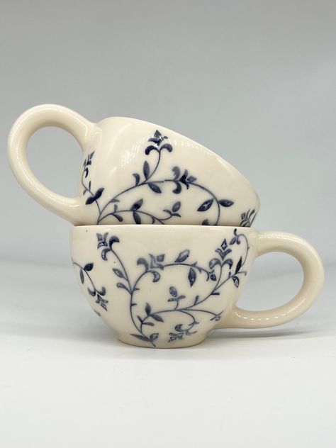 Introducing our charming Rustic Blue Floral Ceramic Mug, a delightful addition to your morning routine or relaxing evening tea time. Handcrafted with care and featuring a beautiful floral design in calming shades of blue, this mug is as functional as it is stylish. The rustic finish adds a touch of antique charm, making it the perfect choice for anyone who appreciates artisanal pottery. Treat yourself or surprise a loved one with this unique and lovely ceramic mug that is sure to brighten up any Bowl Patterns Ceramic, Hand Made Ceramic Mugs, Handmade Ceramic Dinnerware, Cottage Core Ceramics, Ceramic Mug Designs Painted, Ceramic Mug Handles, Ceramic Painting Mug, Ceramics Painting Ideas, Mug Patterns