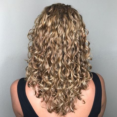 Long curly hair gives off a less voluminous appearance as your locks are pulled down by their natural weight. For a unique and fashion-forward style, choose a V-cut instead of a blunt chop. Tres chic. Curly Hair V Cut, Long Perm, Long Curly Haircuts, Curly Cut, Natural Curly Hair Cuts, Blonde Hairstyle, Bob Haircut Curly, Curly Hair Types, Blonde Curly Hair