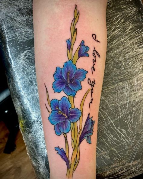 Blue gladiolus tattoo with words I love you Purple Gladiolus Tattoo, Gladiolus Tattoo Small, Blue Gladiolus Flower, Tattoo Small Behind Ear, Gladioli Tattoo, Gladiolus Flower Tattoo, Gladiolus Flower Tattoos, Tattoo With Words, Tiger Lily Tattoos