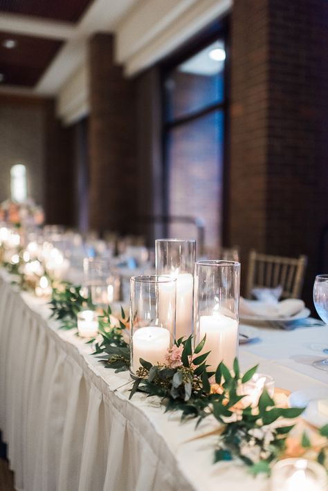 Head table decorated with green ruscus with a collection of cylinder candles and the bridal bouquet. Designed by Phillip's Flowers. Image by Laura Meyer Photography. Head Table Wedding Decorations, Wedding Head Table, Wedding Top Table, Wedding Candles Table, Bridal Party Tables, Head Table Decor, Cylinder Candles, Head Table Wedding, Decoration Evenementielle