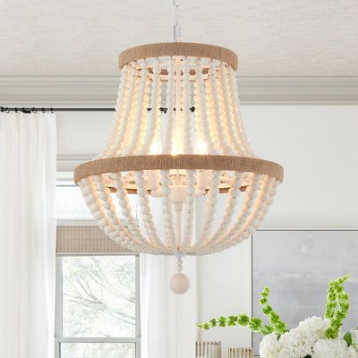 Crafted from metal(white-finished) and wood beads, this fixture features two tiers of rings in the hemp ropes decor for a traditional touch. Strands of oak-white wood beads create a cage and hang below for a splash of glamour. This 3-light statement chandelier brings a glam feel and ambient light to your space. This fixture is height-adjustable, sloped-ceiling adaptable, and dimmer-switch compatible. It accommodates 60W bulbs (sold separately) and complements design styles from bohemian to moder Chandelier Wood, Chandelier Farmhouse, Boho Chandelier, Gold Ceiling Light, Wood Bead Chandelier, Wood Light Fixture, Bedroom Pendant, Rope Decor, Pendant Lighting Bedroom